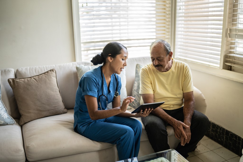 The patient experience of vascular access - a Facebook survey - Mid adult nurse using digital tablet while talking to a senior man in a consultation